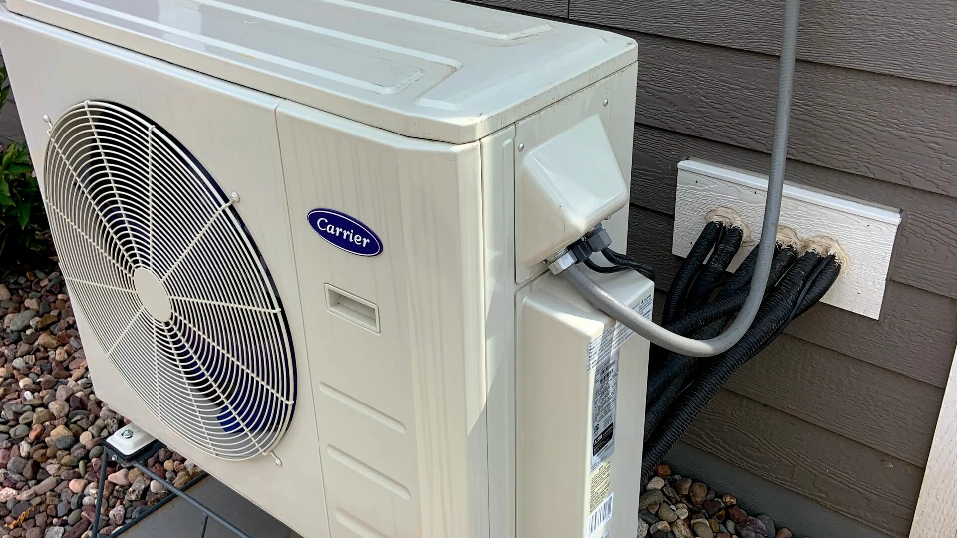 Outdoor air conditioning unit installed on a weatherboard house wall