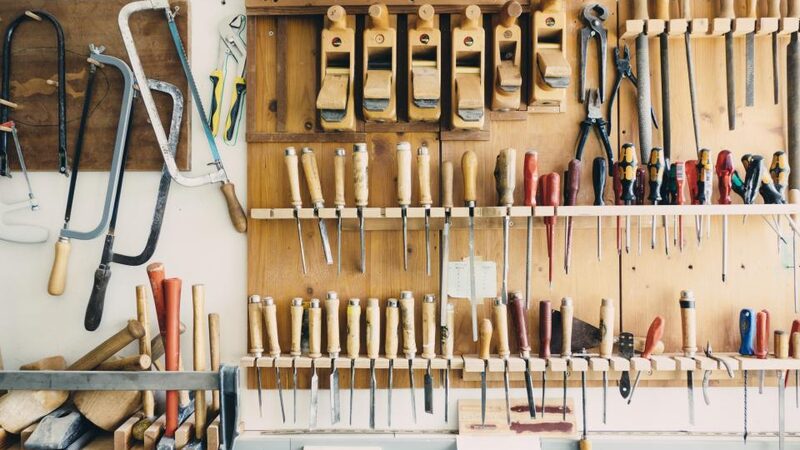 Hand tools arranged on a workshop wall above a bench